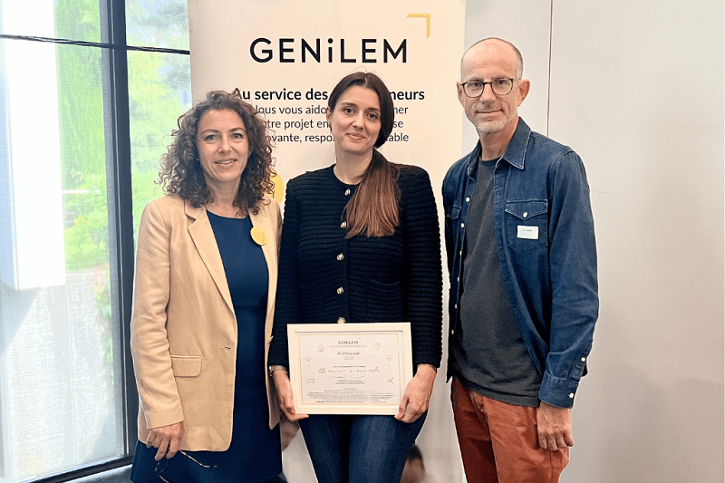 Aurélie Bon, fondatrice de Red drop LAB, reçoit un certificat de soutien de GENILEM, entourée de deux membres de l’organisation.
