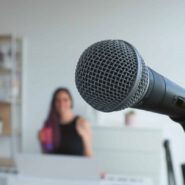 Microphone en premier plan avec Alexia Robert floue en arrière-plan dans son studio vocal à Gland.