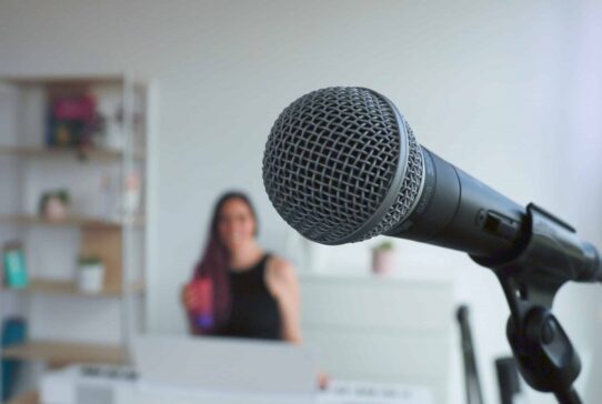 Microphone en premier plan avec Alexia Robert floue en arrière-plan dans son studio vocal à Gland.