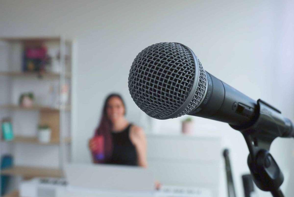 Microphone en premier plan avec Alexia Robert floue en arrière-plan dans son studio vocal à Gland.