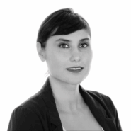 Portrait de Nassime Zafarsani, souriante en tenue professionnelle, sur fond blanc