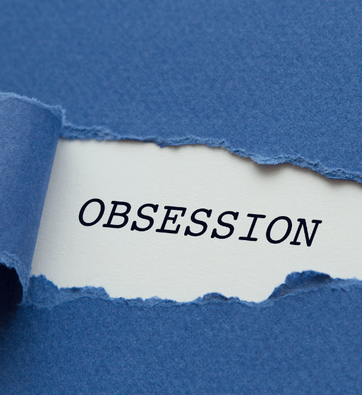 L’image montre un morceau de papier bleu déchiré, laissant apparaître un fond blanc où est inscrit le mot OBSESSION en lettres capitales noires