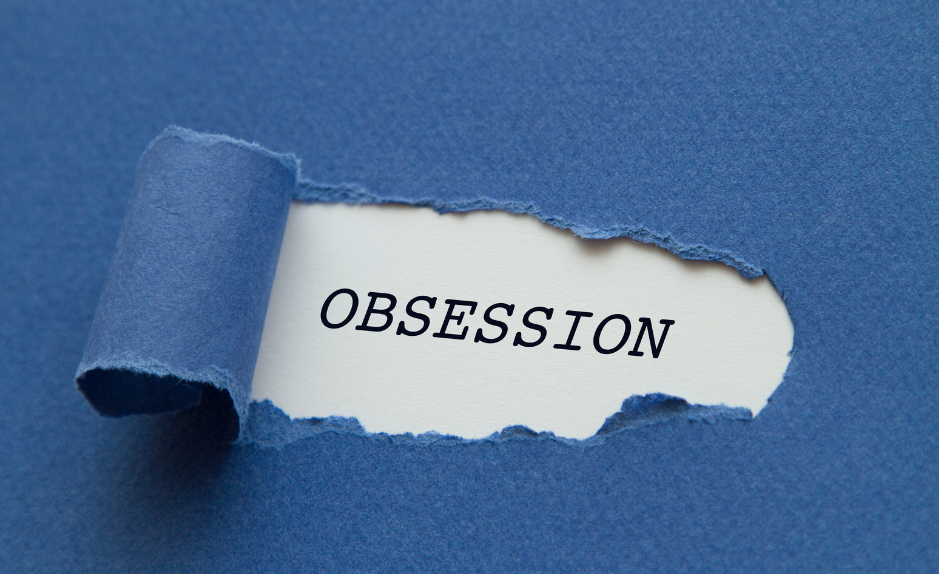 L’image montre un morceau de papier bleu déchiré, laissant apparaître un fond blanc où est inscrit le mot OBSESSION en lettres capitales noires