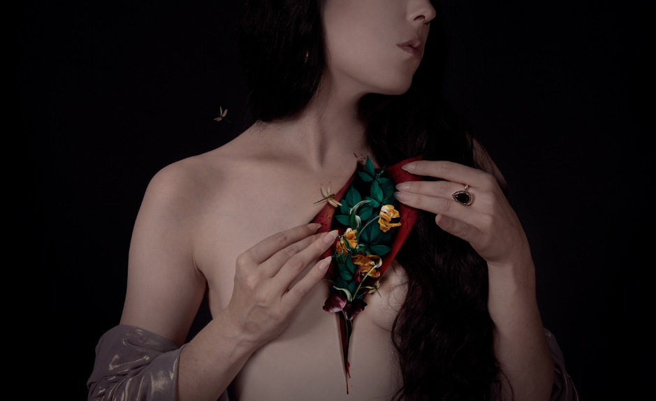 Autoportrait photographique d’Audrey Piguet montrant un buste féminin nu, la poitrine entrouverte révélant des fleurs et des feuilles, sur fond sombre.