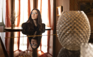 Veronica Fusaro assise au piano dans un intérieur élégant, reflet sur le clavier, lumière naturelle en arrière-plan.