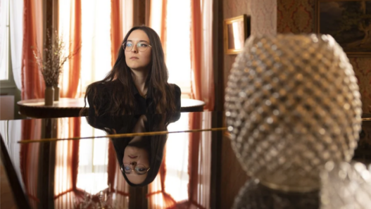 Veronica Fusaro assise au piano dans un intérieur élégant, reflet sur le clavier, lumière naturelle en arrière-plan.