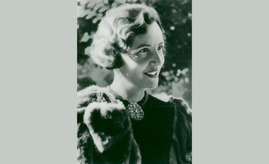 Portrait en noir et blanc d’Antoinette Quinche, juriste suisse et figure du suffrage féminin, souriante en tenue élégante.