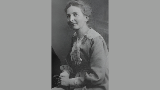 Portrait d’Hélène Monastier, enseignante vaudoise et figure du pacifisme en Suisse romande, assise en robe claire, début du XXe siècle.