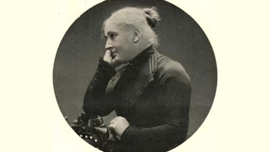 Louise Cornaz, portrait photographique ancien en noir et blanc : vue de profil, cheveux gris relevés en chignon, tenue sombre, main près du visage.