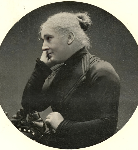 Louise Cornaz, portrait photographique ancien en noir et blanc : vue de profil, cheveux gris relevés en chignon, tenue sombre, main près du visage.