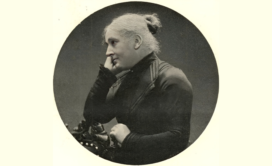 Louise Cornaz, portrait photographique ancien en noir et blanc : vue de profil, cheveux gris relevés en chignon, tenue sombre, main près du visage.