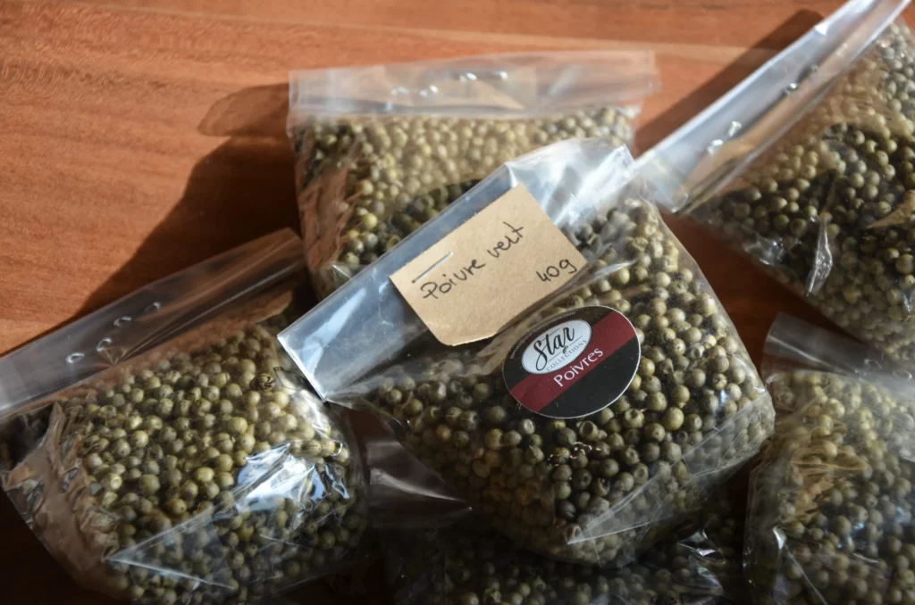 Sachets transparents de poivre vert en grains posés sur une table en bois, avec étiquette manuscrite et conditionnement Star Collections.