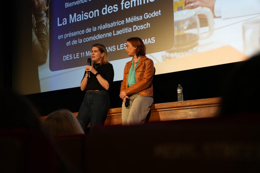 Mélisa Godet et Laetitia Dosch debout sur la scène du Cinéma Odéon, micro à la main, devant l’écran affichant le titre « La Maison des femmes » lors d’une discussion après la projection.