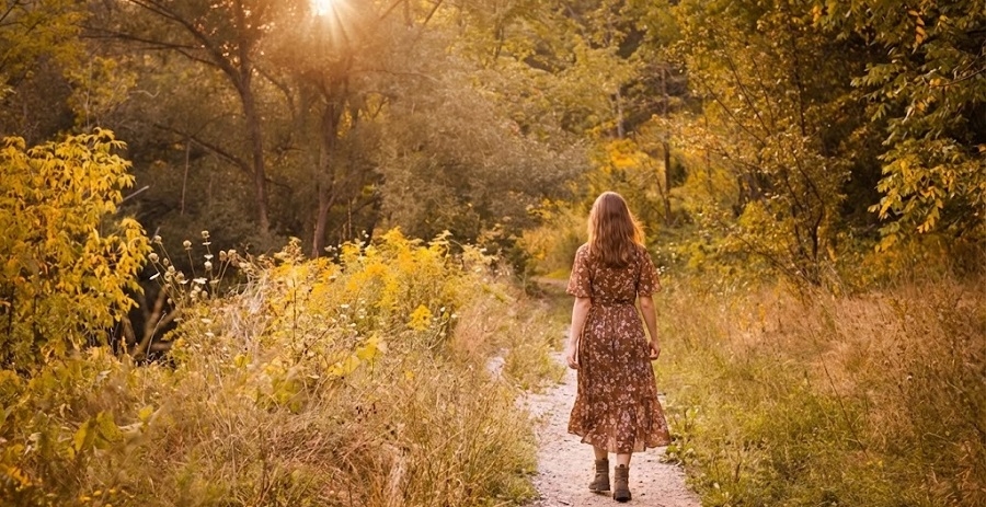 Femme marchant calmement sur un sentier en pleine nature, illustrant un moment de recentrage et d’apaisement émotionnel.