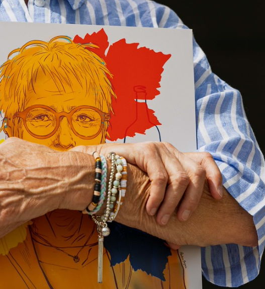 Personne tenant une illustration colorée d’un portrait féminin, créée pour les 30 ans de la loi sur l’égalité en Valais.
