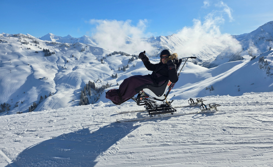 Julie Champenois pratiquant le handiski sur une piste enneigée en montagne.