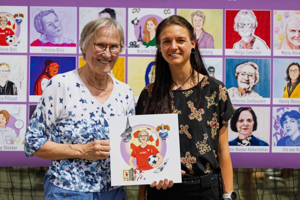 Madeleine Boll et l’illustratrice Soraya Poulin posent devant les portraits de l’initiative valaisanne « 30 femmes – 30 portraits ».