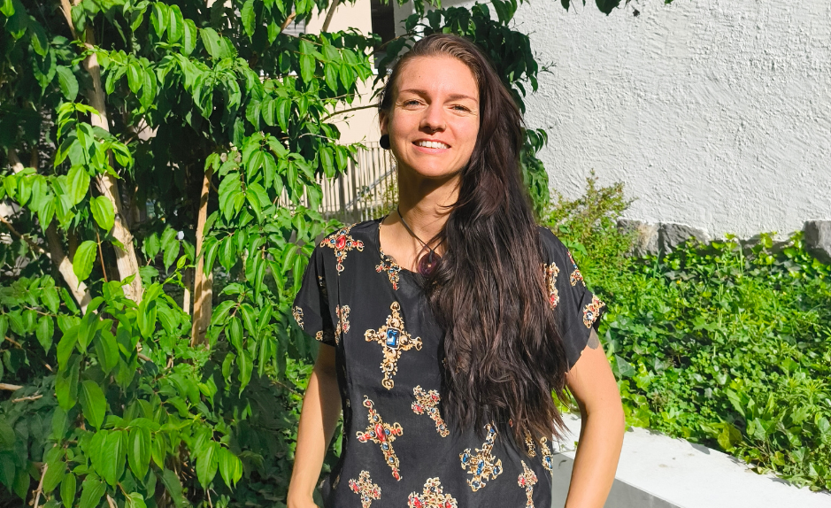 Portrait de Soraya Poulin souriante en extérieur, devant des plantes vertes et un mur blanc.