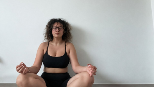 Femme assise au sol les yeux fermés pendant une session de cohérence cardiaque, en posture calme et confortable.