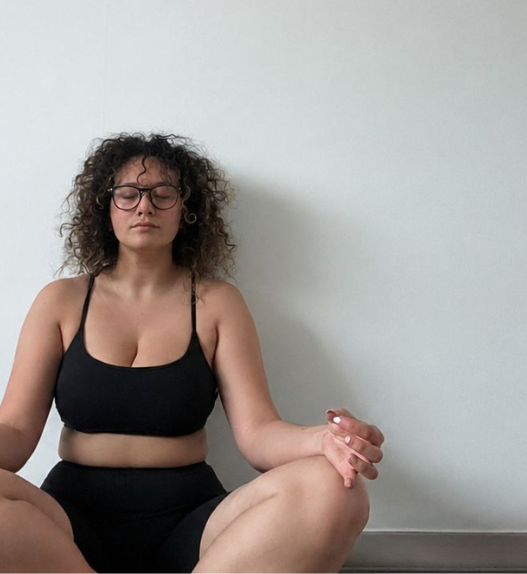 Femme assise au sol les yeux fermés pendant une session de cohérence cardiaque, en posture calme et confortable.