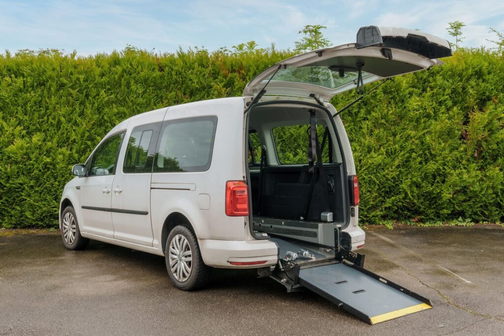 Véhicule adapté PMR avec rampe déployée à l’arrière pour permettre l’accès à une personne en fauteuil roulant.