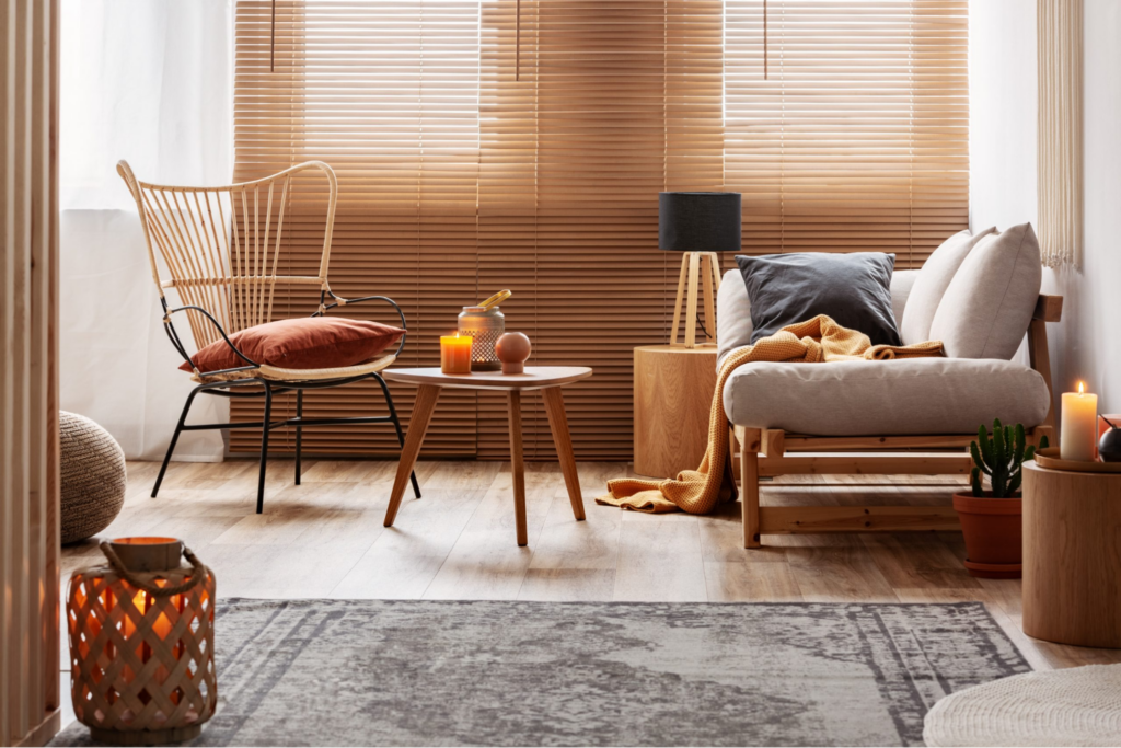 Salon chaleureux aux tons naturels avec fauteuils, canapé, mobilier en bois, bougies et plaid couleur moutarde.