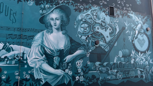 Fresque murale à Bulle représentant une femme, des engrenages et des scènes de la vie en Gruyère