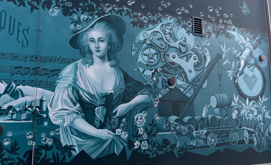 Fresque murale à Bulle représentant une femme, des engrenages et des scènes de la vie en Gruyère