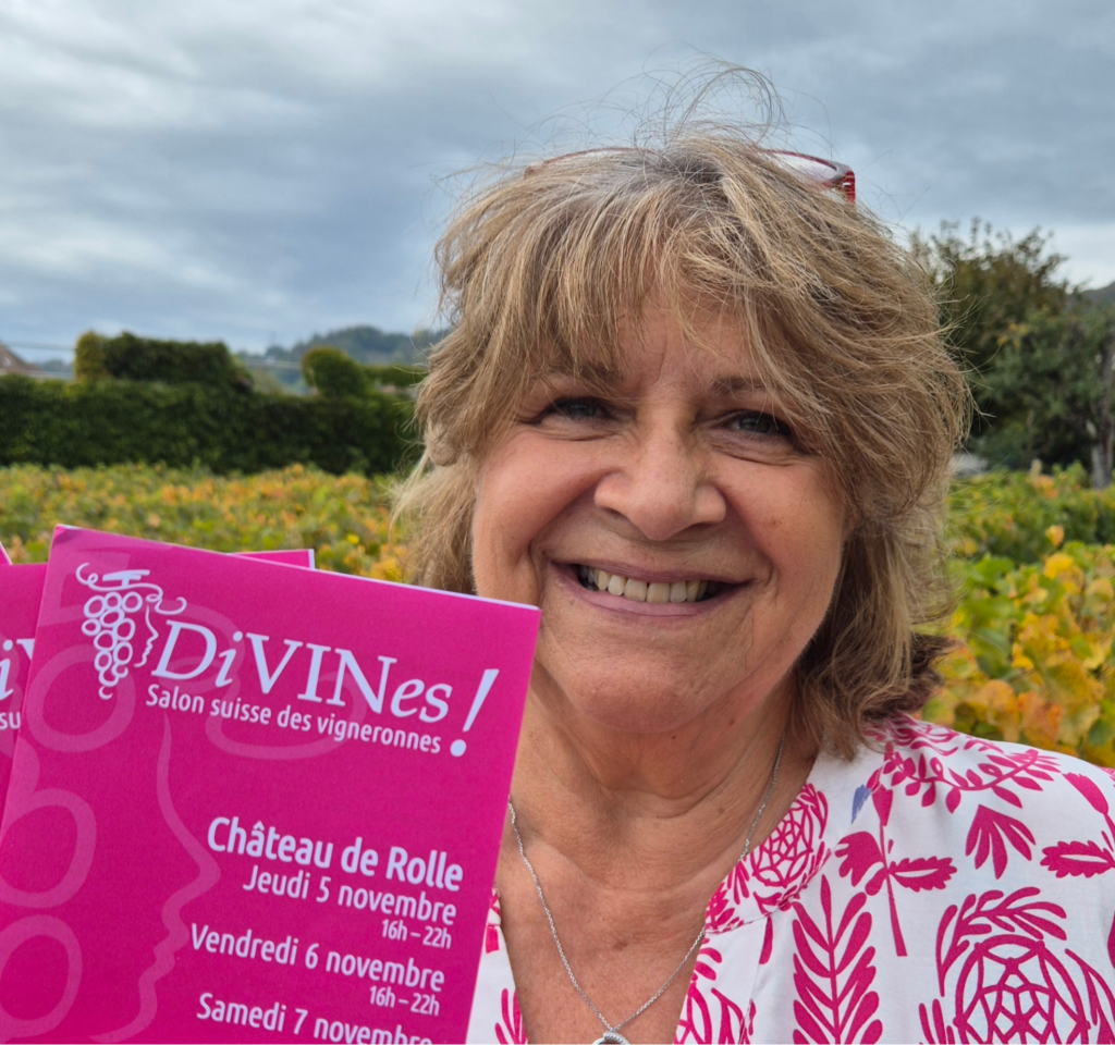 Nadège Fehlmann-Bonin, coorganisatrice de DiVINes !, souriante devant les vignes, présente l'affiche du Salon suisse des vigneronnes 2026.