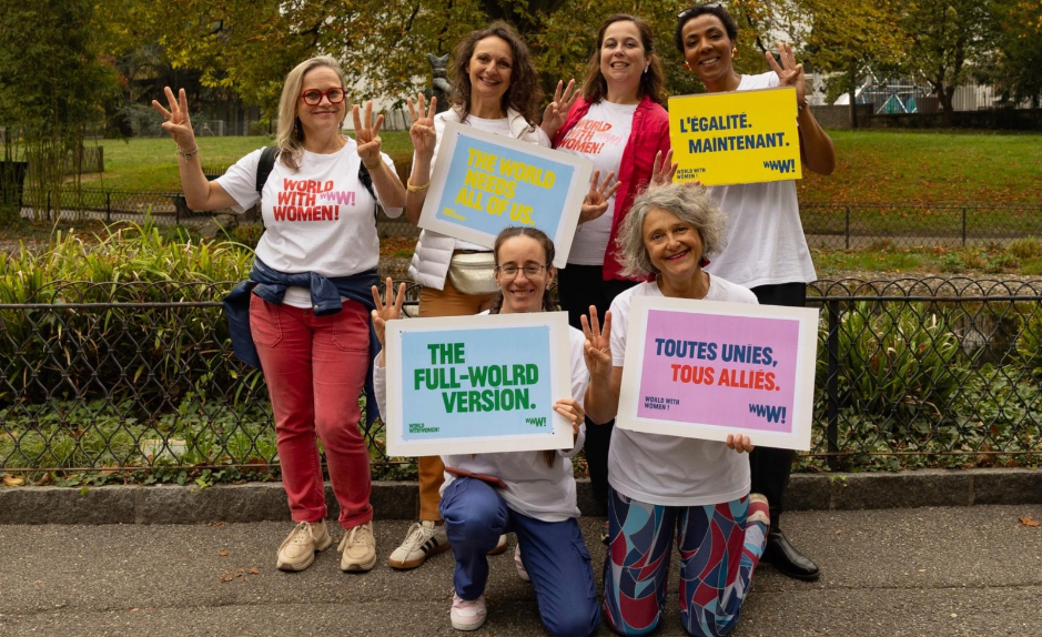 Six participantes à World with Women Switzerland posant dans un parc avec des pancartes en faveur de l’égalité.